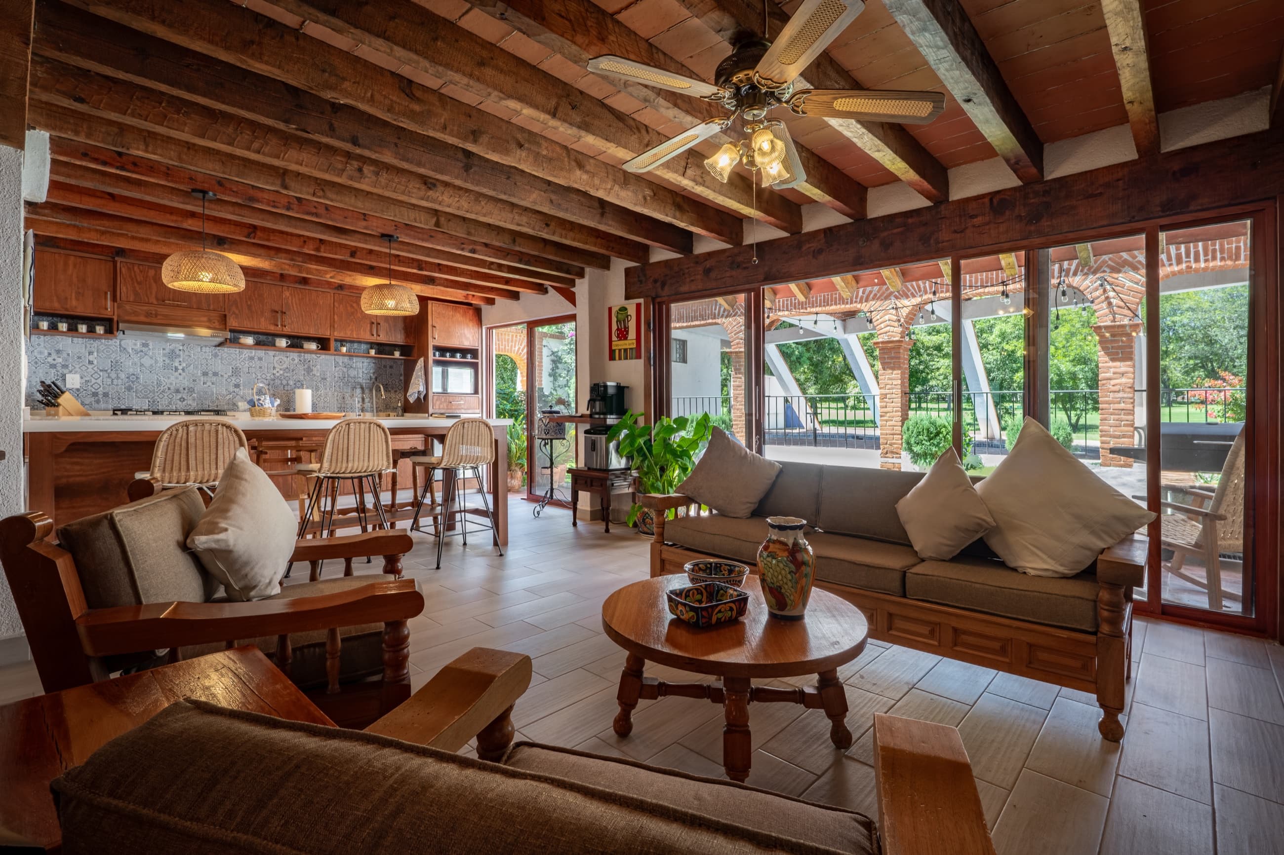 Sala y cocina de una casa de campo en Tequisquiapan, con detalles de talavera y vista al jardín y la alberca.